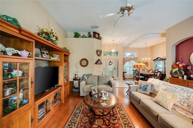 living room with ceiling fan with notable chandelier and hardwood / wood-style floors