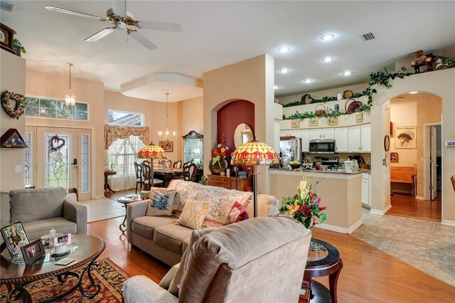 living room with ceiling fan with notable chandelier and light hardwood / wood-style flooring