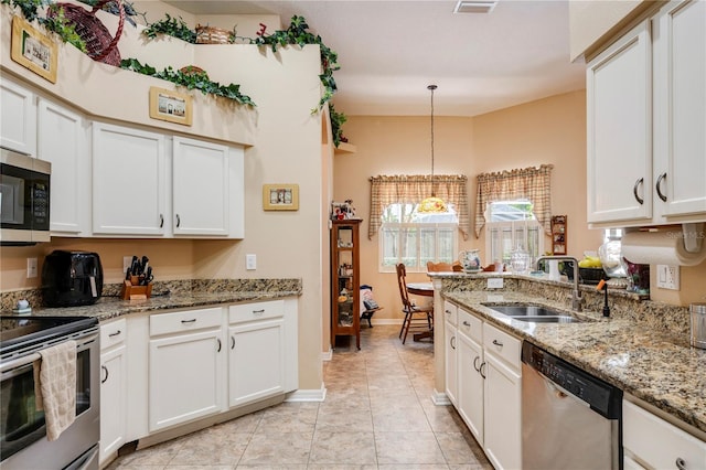 kitchen with pendant lighting, white cabinets, sink, appliances with stainless steel finishes, and light stone countertops