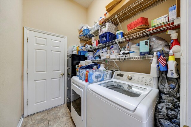 laundry room with washing machine and clothes dryer and light tile patterned floors