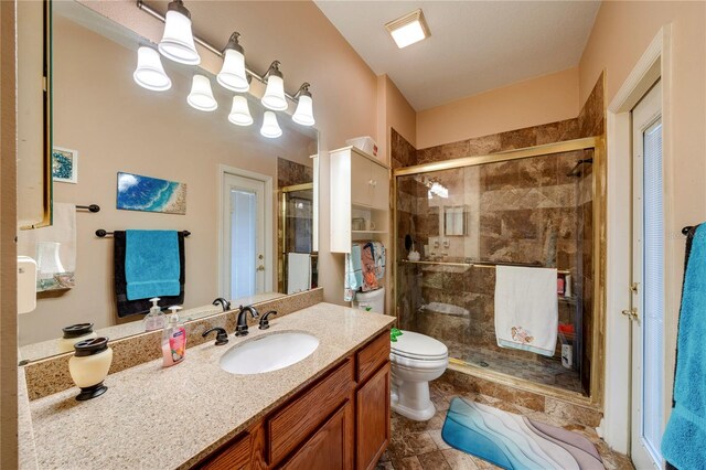 bathroom with vanity, a shower with shower door, and toilet