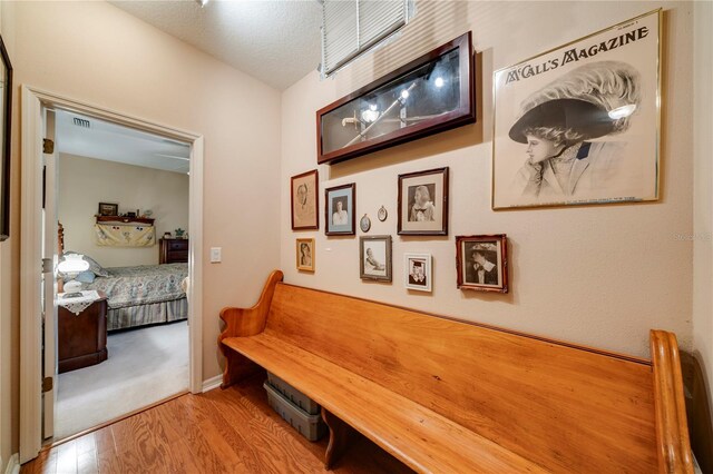 corridor with a textured ceiling and light hardwood / wood-style floors