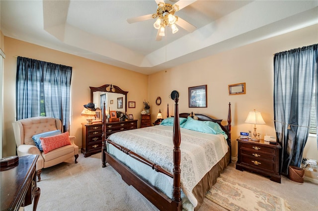 carpeted bedroom with a tray ceiling and ceiling fan