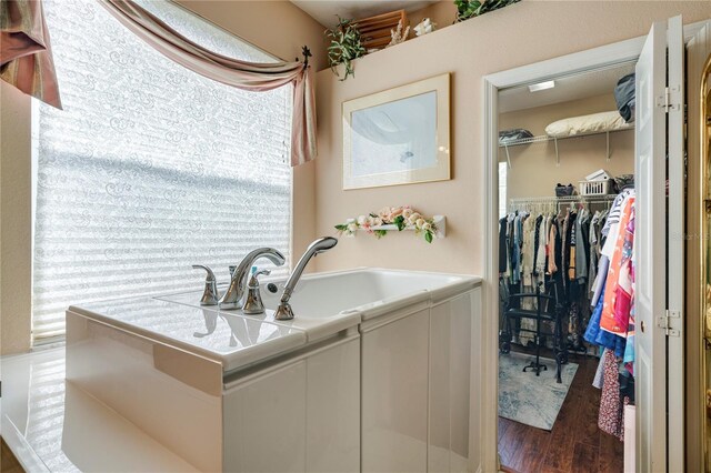 bathroom with a tub to relax in and wood-type flooring