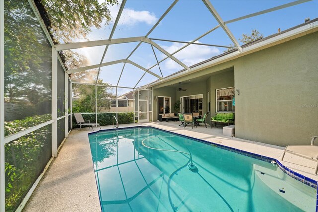 view of swimming pool featuring ceiling fan, a lanai, and a patio