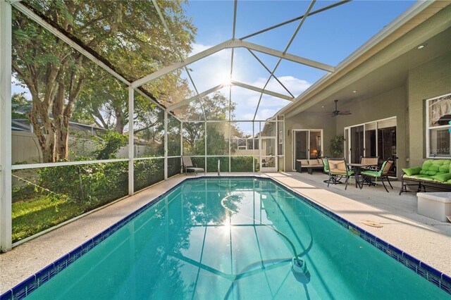 view of swimming pool with ceiling fan, glass enclosure, and a patio area