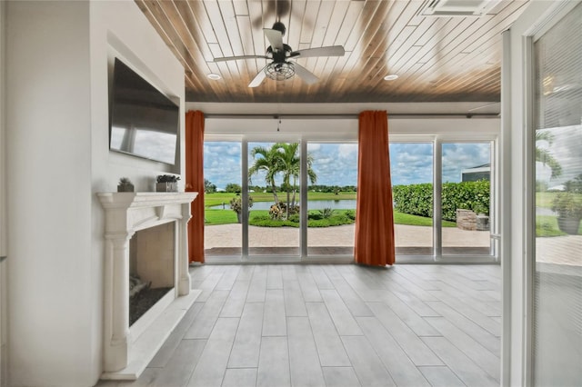 unfurnished living room featuring wooden ceiling, ceiling fan, plenty of natural light, and light wood-type flooring