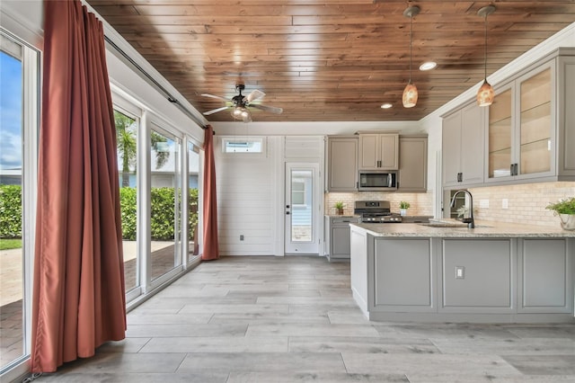 kitchen featuring pendant lighting, light wood-type flooring, tasteful backsplash, kitchen peninsula, and appliances with stainless steel finishes