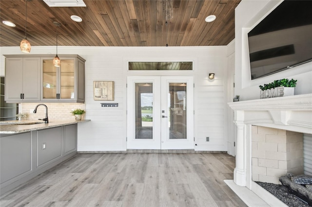 interior space with light hardwood / wood-style floors, wood walls, light stone counters, and decorative light fixtures