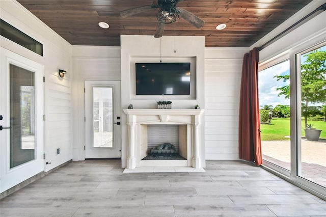 unfurnished living room with light hardwood / wood-style flooring, wood walls, ceiling fan, and wooden ceiling