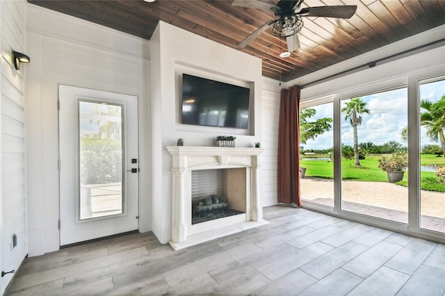 unfurnished living room with wooden ceiling, a healthy amount of sunlight, and ceiling fan