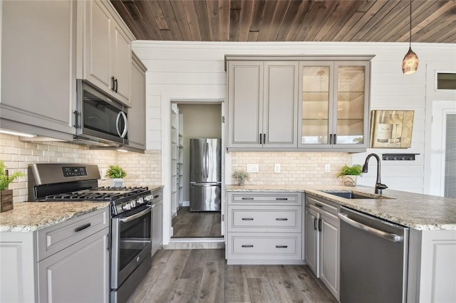 kitchen with gray cabinets, hardwood / wood-style flooring, sink, appliances with stainless steel finishes, and decorative light fixtures