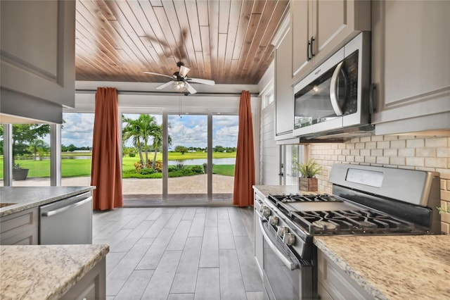 kitchen with appliances with stainless steel finishes, decorative backsplash, a water view, wooden ceiling, and ceiling fan