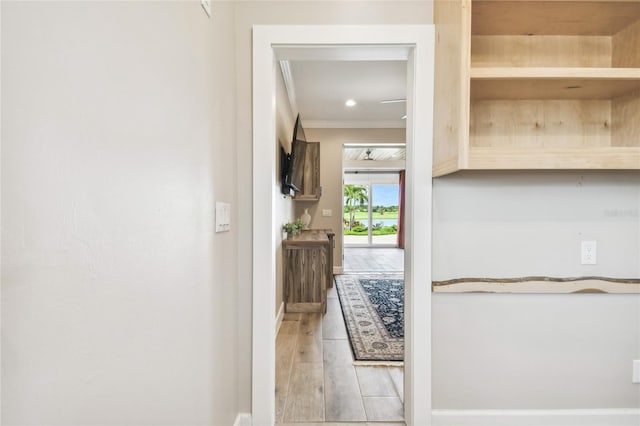 hall with light hardwood / wood-style floors and ornamental molding