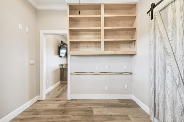 interior space featuring a barn door, crown molding, and hardwood / wood-style flooring