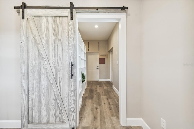 corridor with wood-type flooring and a barn door