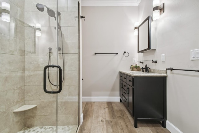 bathroom featuring ornamental molding, hardwood / wood-style floors, a shower with door, and vanity