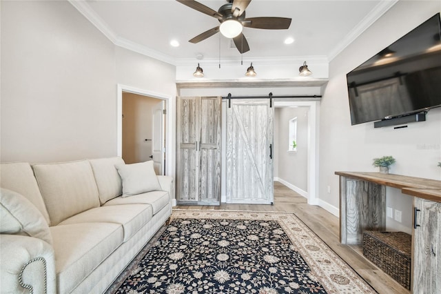 living room featuring a barn door, ornamental molding, ceiling fan, and light hardwood / wood-style flooring