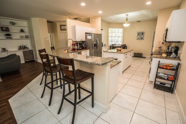 kitchen featuring pendant lighting, tasteful backsplash, kitchen peninsula, light hardwood / wood-style flooring, and stainless steel fridge