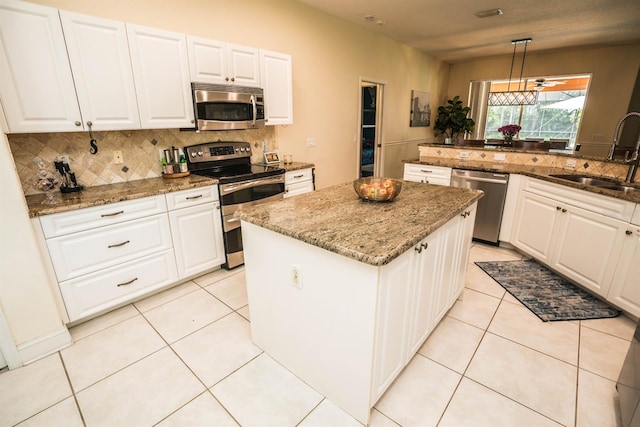 kitchen featuring appliances with stainless steel finishes, hanging light fixtures, white cabinets, a center island, and sink