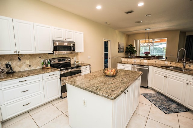 kitchen with pendant lighting, sink, white cabinetry, appliances with stainless steel finishes, and a center island