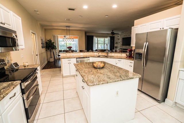 kitchen featuring stainless steel appliances, kitchen peninsula, white cabinetry, and a kitchen island