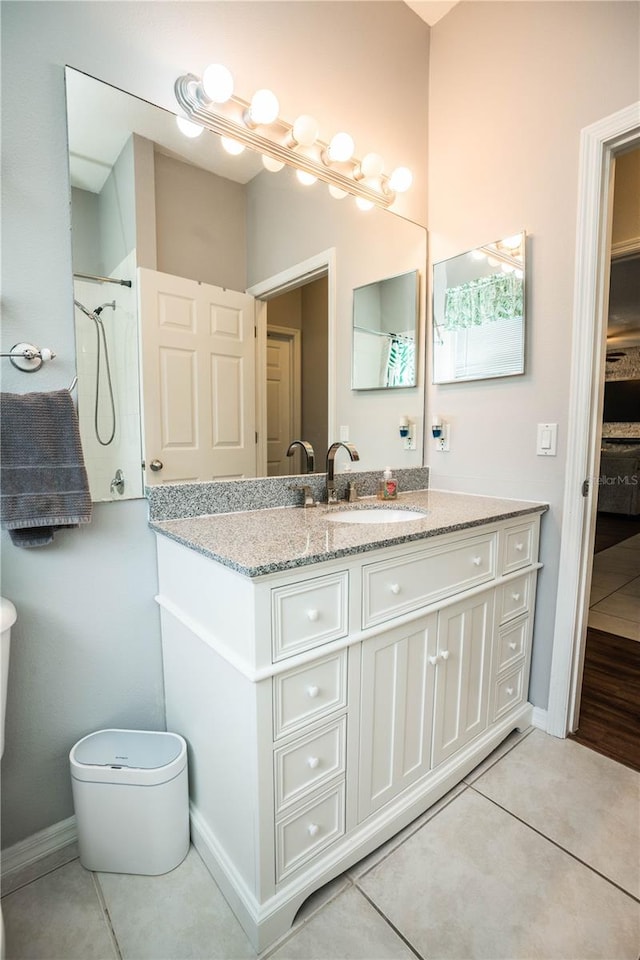 bathroom featuring tile patterned flooring, walk in shower, vanity, and toilet