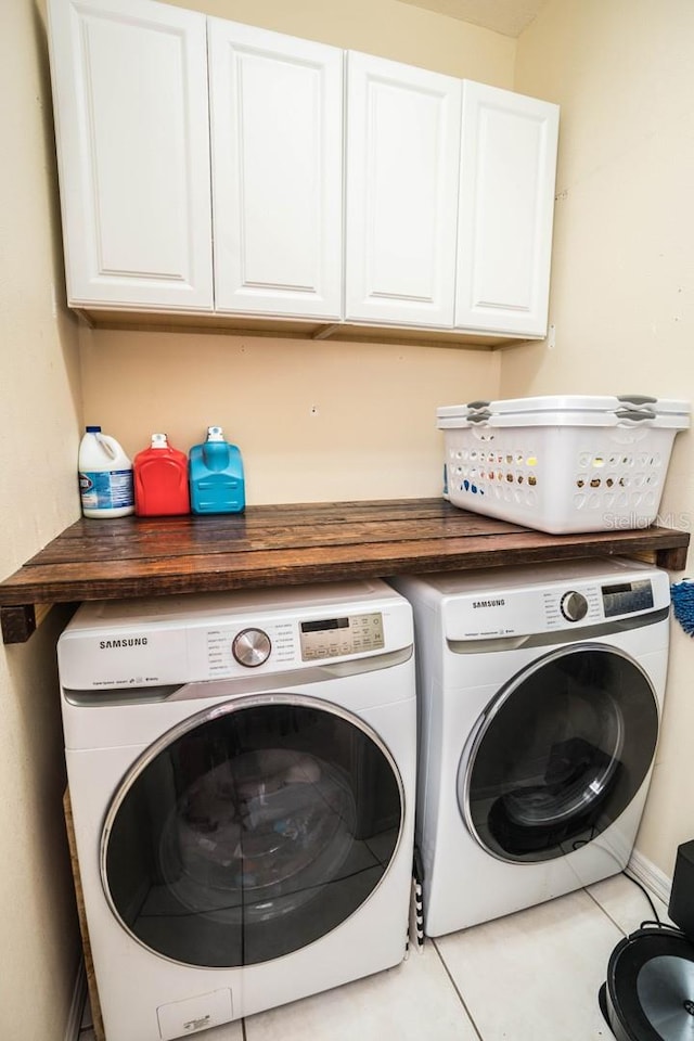 washroom with washing machine and clothes dryer, cabinets, and light tile patterned floors