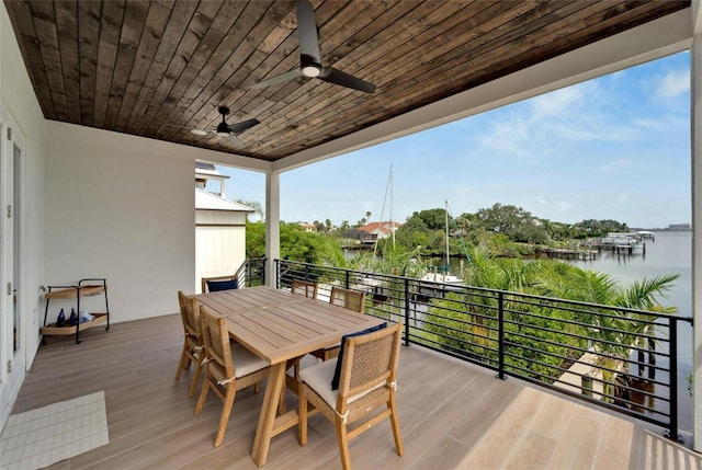 wooden terrace with a water view and ceiling fan