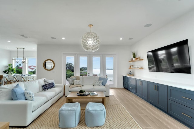 living room featuring plenty of natural light, light hardwood / wood-style flooring, and a notable chandelier