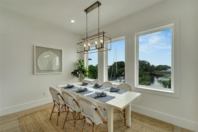 dining room featuring a notable chandelier, light hardwood / wood-style flooring, and a water view