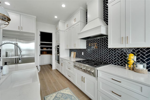 kitchen with white cabinets, appliances with stainless steel finishes, and custom range hood