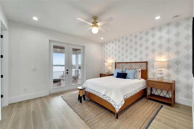 bedroom with light wood-type flooring, access to exterior, a water view, ceiling fan, and french doors