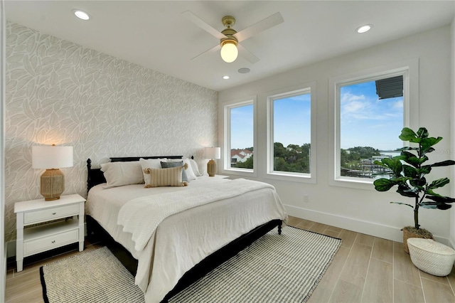 bedroom featuring multiple windows, ceiling fan, and light hardwood / wood-style flooring