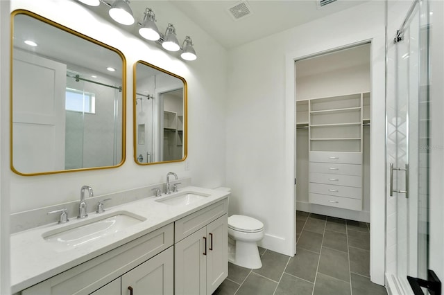 bathroom featuring vanity, a shower with door, tile patterned floors, and toilet