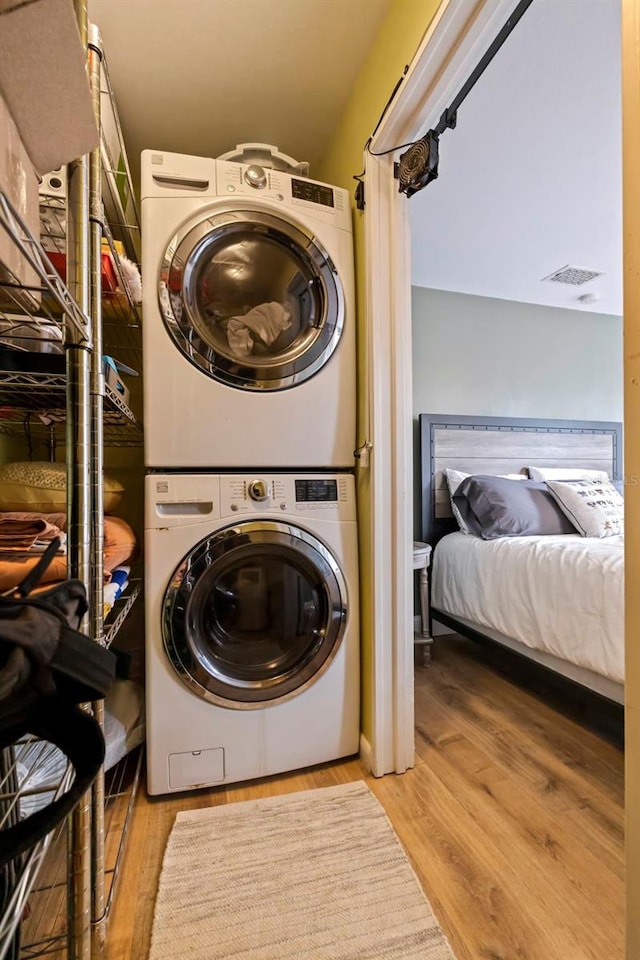 clothes washing area with stacked washer / drying machine and light wood-type flooring