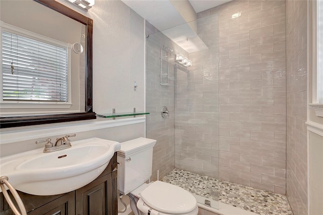 bathroom with a tile shower, vanity, and toilet