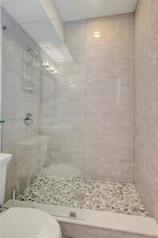 bathroom featuring a tile shower and toilet