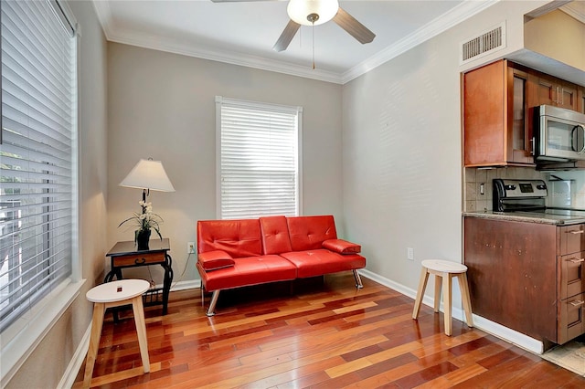 living area featuring ceiling fan, light wood-type flooring, and ornamental molding