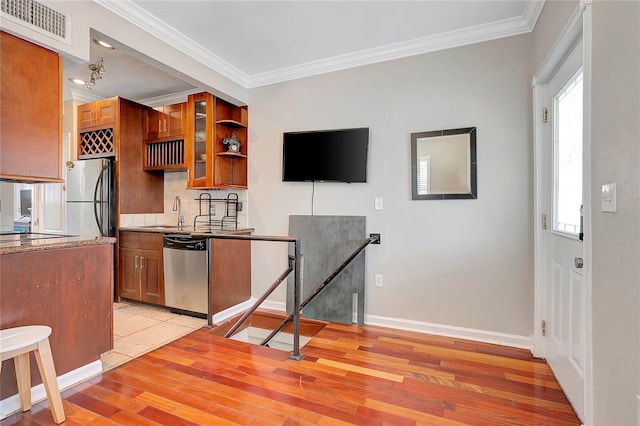 kitchen featuring ornamental molding, stainless steel appliances, backsplash, and light hardwood / wood-style floors