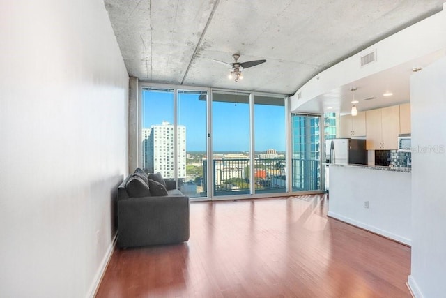 unfurnished living room featuring ceiling fan, a wall of windows, and a wealth of natural light