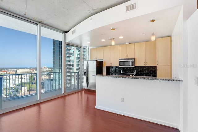 kitchen featuring plenty of natural light, dark stone countertops, stainless steel appliances, and hanging light fixtures