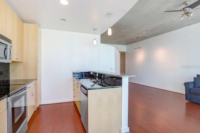 kitchen featuring kitchen peninsula, decorative backsplash, appliances with stainless steel finishes, pendant lighting, and dark hardwood / wood-style floors