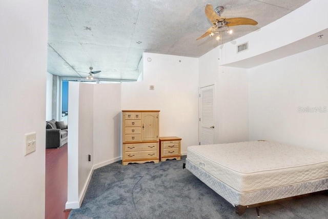 bedroom with dark colored carpet, ceiling fan, and a closet