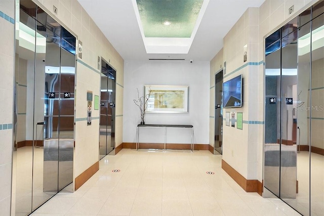 hall featuring light tile patterned flooring and elevator