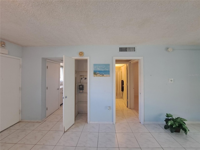 interior space featuring light tile patterned floors, a textured ceiling, and ensuite bathroom