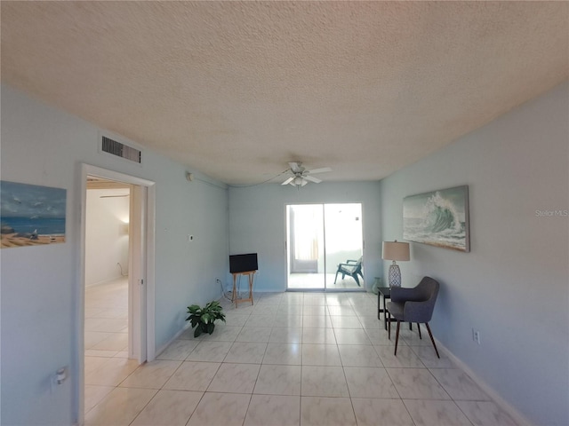 interior space featuring ceiling fan, light tile patterned floors, and a textured ceiling