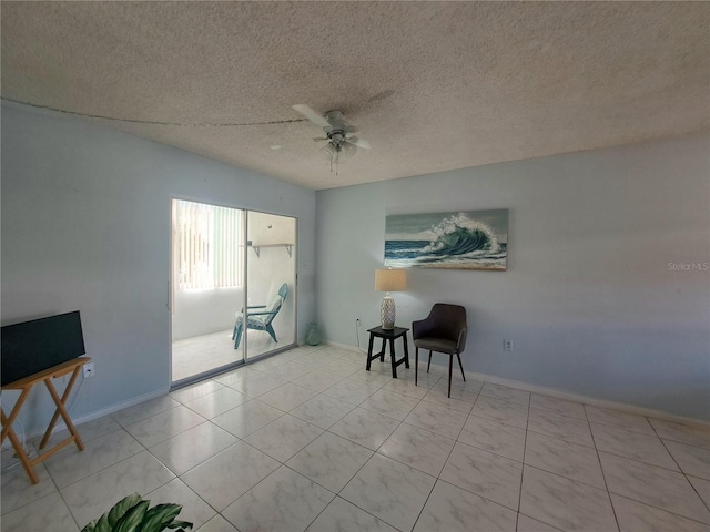 living area with ceiling fan and a textured ceiling