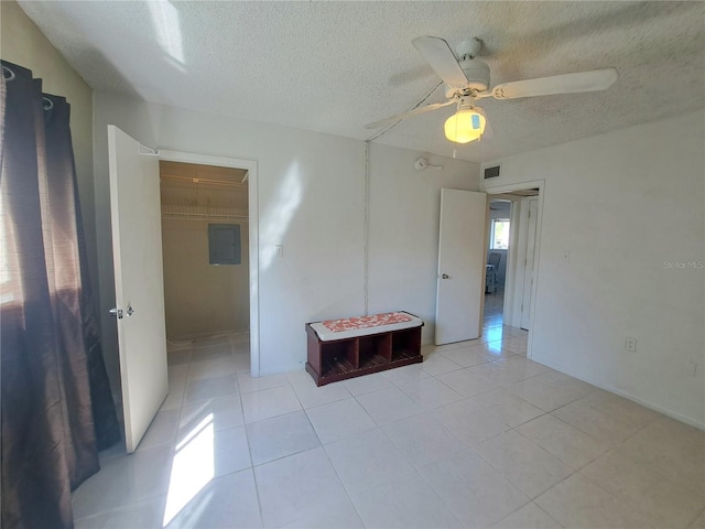 spare room featuring ceiling fan, electric panel, light tile patterned floors, and a textured ceiling