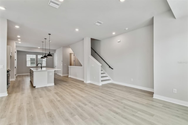 unfurnished living room featuring sink and light hardwood / wood-style floors